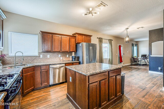 401 Everlook Ln, Horizon City, TX 79928 - kitchen featuring stainless steel appliances, dark wood-type flooring, decorative backsplash, a center island, and light stone countertops