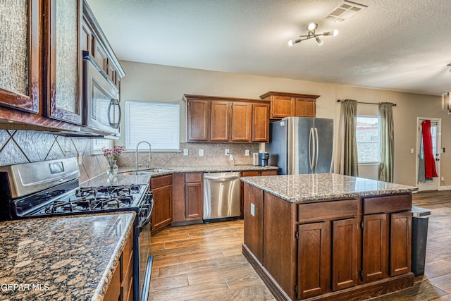 401 Everlook Ln, Horizon City, TX 79928 - kitchen featuring stainless steel appliances, light wood-style floors, decorative backsplash, a kitchen island, and a textured ceiling