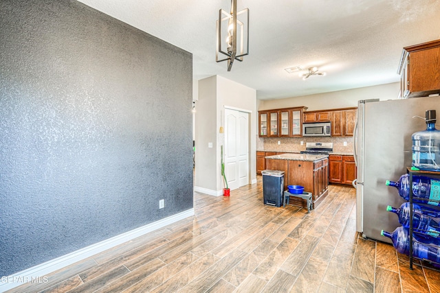 401 Everlook Ln, Horizon City, TX 79928 - kitchen featuring appliances with stainless steel finishes, brown cabinets, light wood finished floors, and a center island