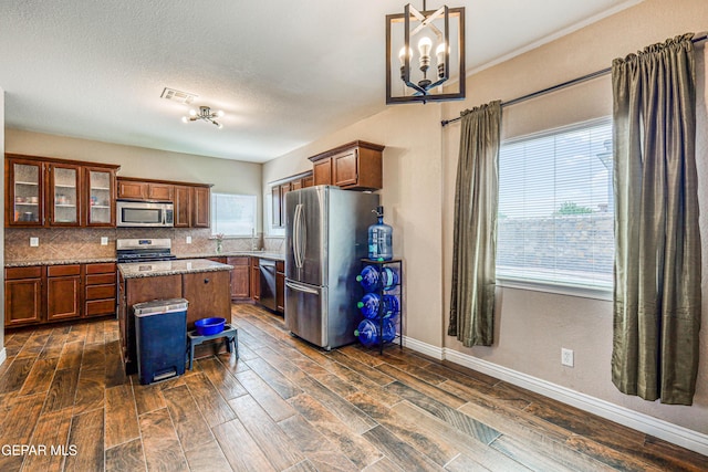 401 Everlook Ln, Horizon City, TX 79928 - kitchen featuring appliances with stainless steel finishes, a kitchen island, dark wood-style floors, and backsplash