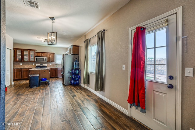401 Everlook Ln, Horizon City, TX 79928 - kitchen with appliances with stainless steel finishes, dark wood-type flooring, a kitchen island, a chandelier, and a textured wall