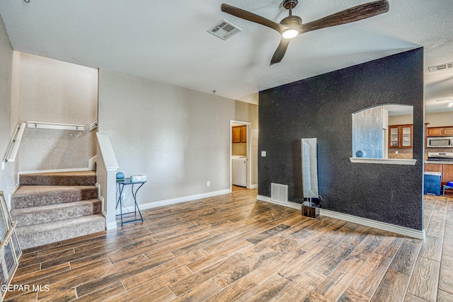 401 Everlook Ln, Horizon City, TX 79928 - unfurnished living room featuring wood finished floors, a ceiling fan, washer / clothes dryer, stairway, and a textured ceiling