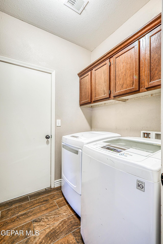 401 Everlook Ln, Horizon City, TX 79928 - laundry area featuring dark wood-style floors, cabinet space, washing machine and clothes dryer, and a textured ceiling