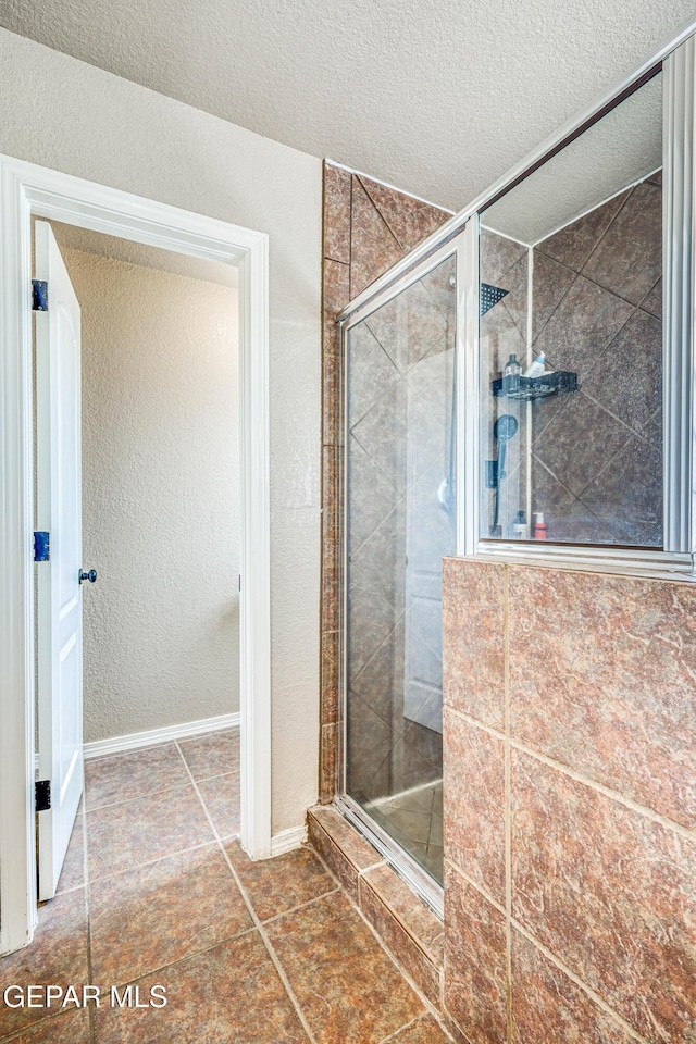 401 Everlook Ln, Horizon City, TX 79928 - bathroom with a stall shower, a textured ceiling, a textured wall, and tile patterned flooring