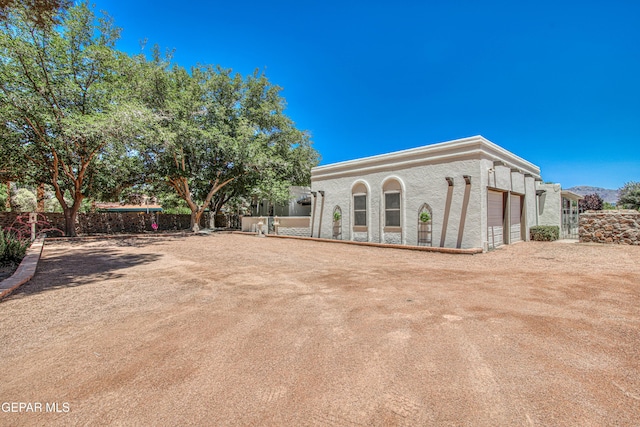 5430 Davis Cup Ct, El Paso, TX 79932 - back of house featuring dirt driveway, a garage, and stucco siding