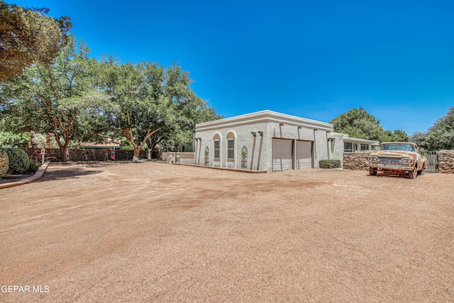 5430 Davis Cup Ct, El Paso, TX 79932 - back of property featuring an attached garage, dirt driveway, and stucco siding