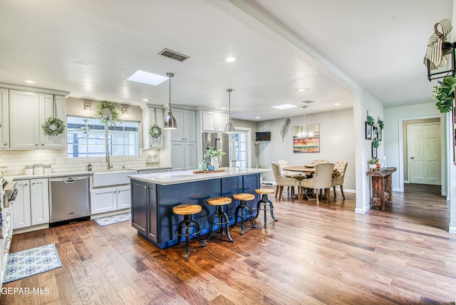 5430 Davis Cup Ct, El Paso, TX 79932 - kitchen with stainless steel dishwasher, a center island, dark wood finished floors, light countertops, and a breakfast bar