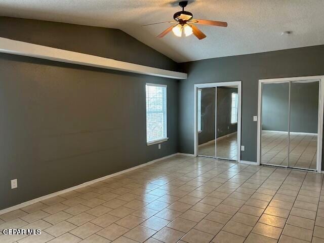 9728 El Tepeyac Ave, El Paso, TX 79927 - unfurnished bedroom featuring multiple closets, lofted ceiling, a textured ceiling, a ceiling fan, and light tile patterned flooring