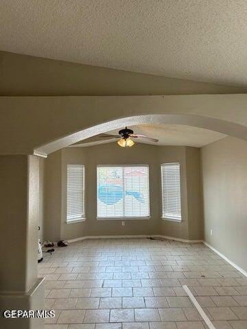 9728 El Tepeyac Ave, El Paso, TX 79927 - empty room with arched walkways, a ceiling fan, a textured ceiling, light tile patterned flooring, and lofted ceiling