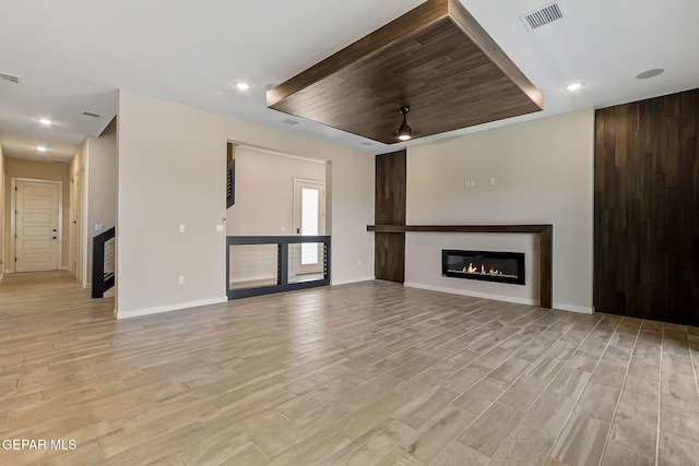 14904 John Mcneely Ave, El Paso, TX 79938 - unfurnished living room with light wood-style floors, a glass covered fireplace, recessed lighting, and a raised ceiling