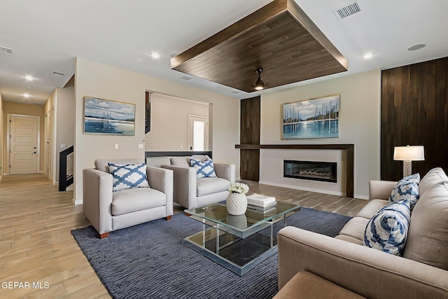 14904 John Mcneely Ave, El Paso, TX 79938 - living area featuring light wood-type flooring, a glass covered fireplace, recessed lighting, and a tray ceiling