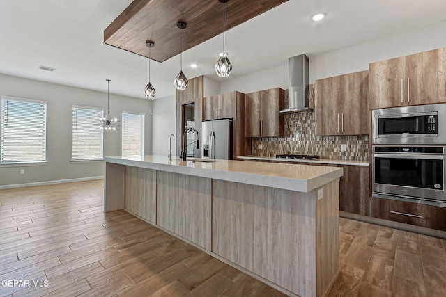 14904 John Mcneely Ave, El Paso, TX 79938 - kitchen featuring appliances with stainless steel finishes, wall chimney exhaust hood, light countertops, decorative backsplash, and a spacious island
