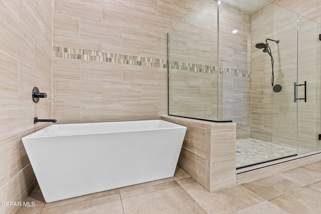 14904 John Mcneely Ave, El Paso, TX 79938 - bathroom with a freestanding tub, a shower stall, tile patterned flooring, and tile walls