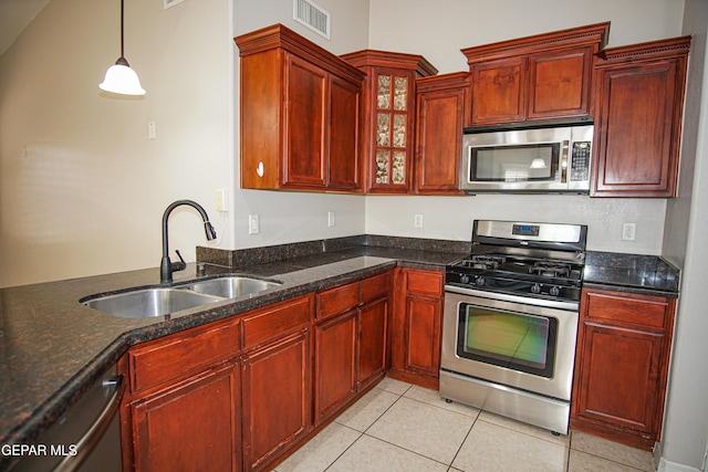 5353 Manuel Puentes Ct, El Paso, TX 79934 - kitchen featuring stainless steel appliances, light tile patterned floors, dark stone countertops, glass insert cabinets, and decorative light fixtures