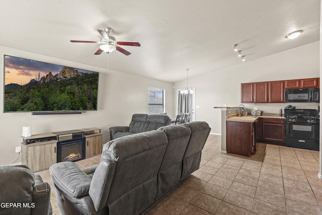 14215 Otter Point Ct, El Paso, TX 79938 - tiled living area with a ceiling fan, vaulted ceiling, a glass covered fireplace, and a chandelier