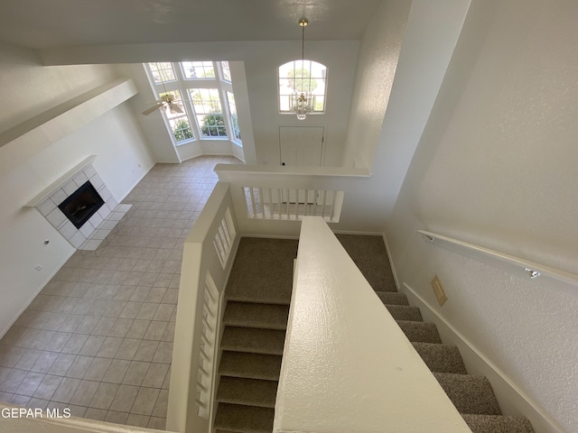 1409 Rainbow Ridge Dr, El Paso, TX 79912 - staircase featuring a chandelier, a ceiling fan, a tiled fireplace, and tile patterned floors