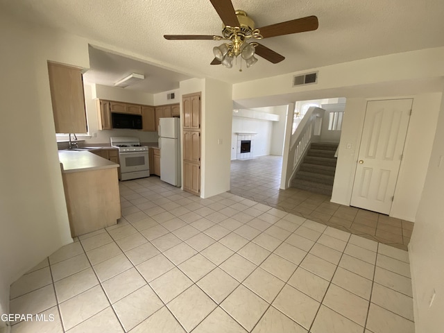 1409 Rainbow Ridge Dr, El Paso, TX 79912 - kitchen featuring white appliances, open floor plan, a fireplace, a ceiling fan, and light tile patterned flooring