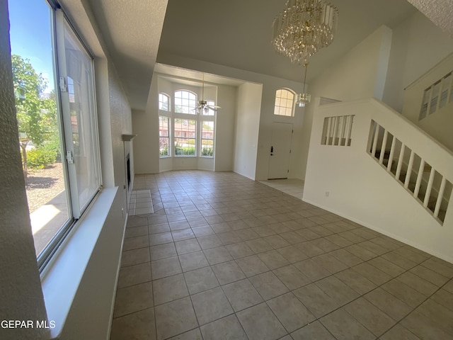 1409 Rainbow Ridge Dr, El Paso, TX 79912 - unfurnished living room with a chandelier, tile patterned floors, stairs, lofted ceiling, and a fireplace