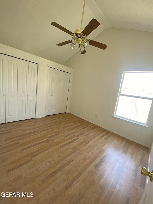1409 Rainbow Ridge Dr, El Paso, TX 79912 - unfurnished bedroom featuring multiple closets, vaulted ceiling, light wood-style flooring, and a ceiling fan