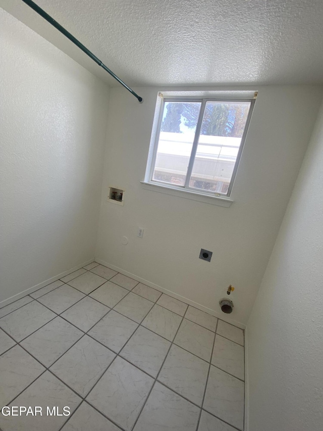1409 Rainbow Ridge Dr, El Paso, TX 79912 - laundry room featuring hookup for a gas dryer, hookup for an electric dryer, hookup for a washing machine, a textured ceiling, and light tile patterned floors