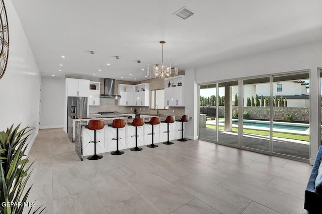 525 Cotton Blossom Ave, El Paso, TX 79922 - kitchen with wall chimney exhaust hood, a breakfast bar, a chandelier, backsplash, and stainless steel fridge