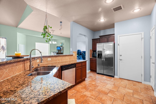 14605 Spanish Point Dr, El Paso, TX 79938 - kitchen with stainless steel appliances, dark stone countertops, decorative backsplash, arched walkways, and light stone finish flooring