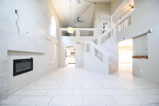 1465 Fito Hernandez St, El Paso, TX 79928 - unfurnished living room with high vaulted ceiling, arched walkways, a glass covered fireplace, a ceiling fan, and stairs