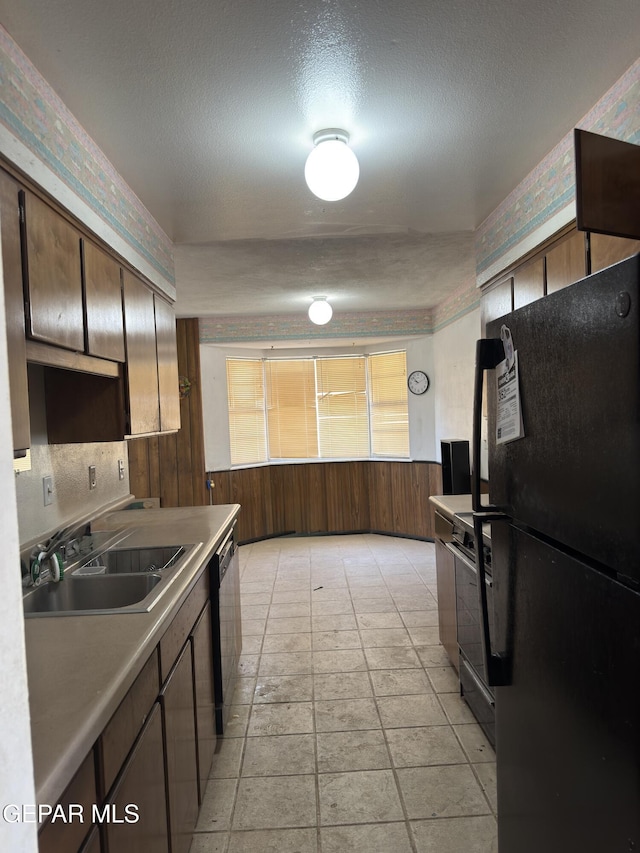 3376 Guthrie St, El Paso, TX 79935 - kitchen featuring freestanding refrigerator, dishwashing machine, stove, a textured ceiling, and a wainscoted wall