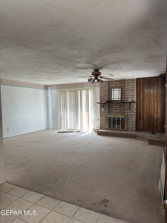 3376 Guthrie St, El Paso, TX 79935 - unfurnished living room featuring light carpet, a fireplace, a ceiling fan, light tile patterned floors, and a textured ceiling
