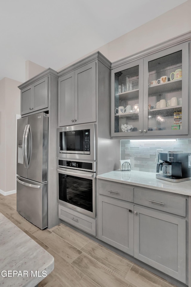 737 Al Smith Ln, El Paso, TX 79932 - kitchen with stainless steel appliances, gray cabinetry, light wood finished floors, and glass insert cabinets