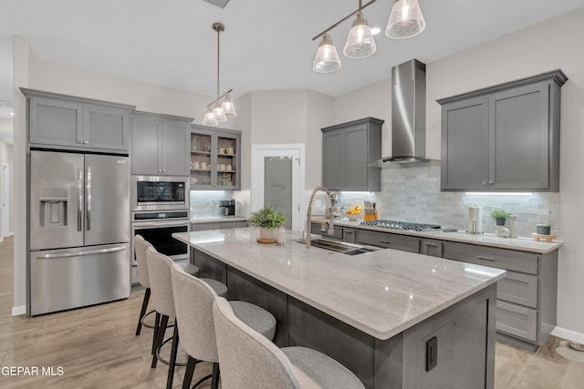 737 Al Smith Ln, El Paso, TX 79932 - kitchen featuring stainless steel appliances, wall chimney range hood, gray cabinetry, light stone counters, and decorative backsplash