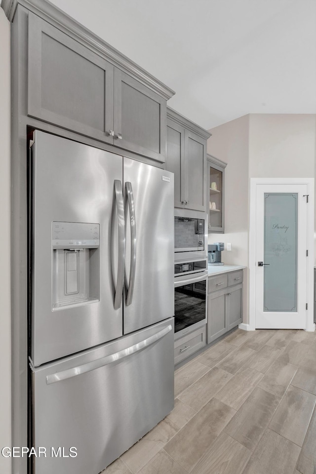 737 Al Smith Ln, El Paso, TX 79932 - kitchen with stainless steel appliances, gray cabinetry, tasteful backsplash, light countertops, and glass insert cabinets