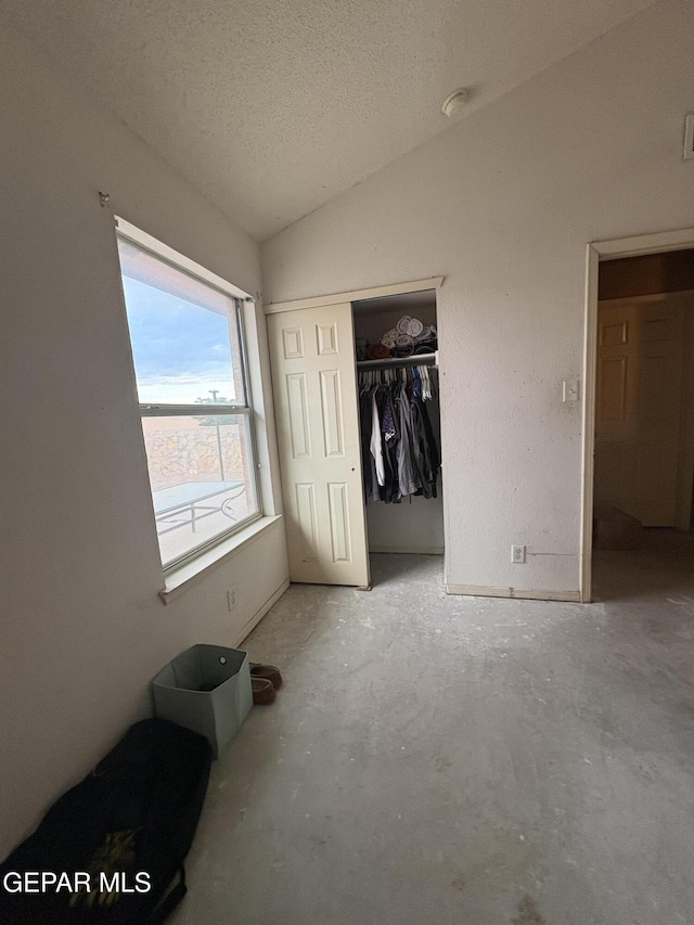 9421 Ariel Rico Ct, El Paso, TX 79907 - unfurnished bedroom with lofted ceiling, unfinished concrete flooring, a closet, and a textured ceiling
