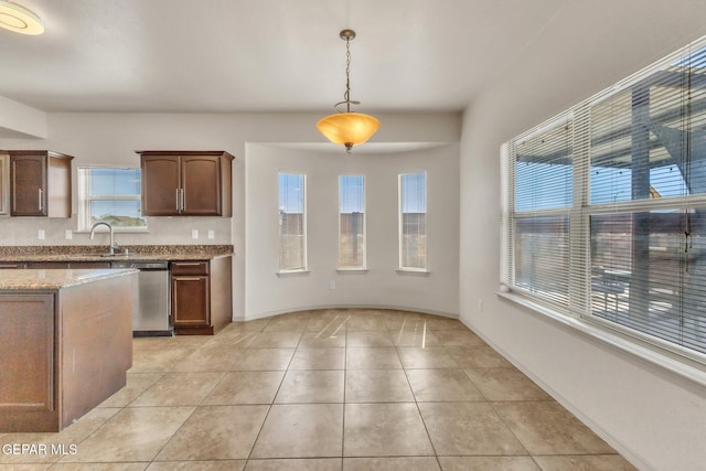 14330 Woods Point Ave, El Paso, TX 79938 - kitchen with stainless steel dishwasher, light tile patterned flooring, light stone counters, and decorative light fixtures