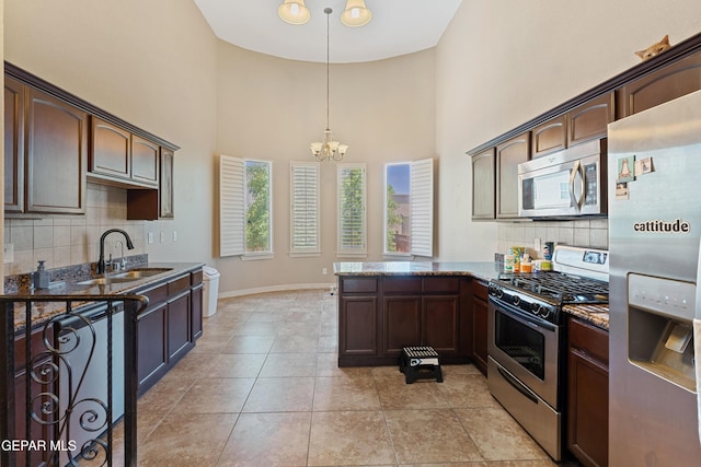 13013 Pleasant Manor Ct, El Paso, TX 79938 - kitchen with appliances with stainless steel finishes, a chandelier, dark stone counters, decorative backsplash, and a high ceiling
