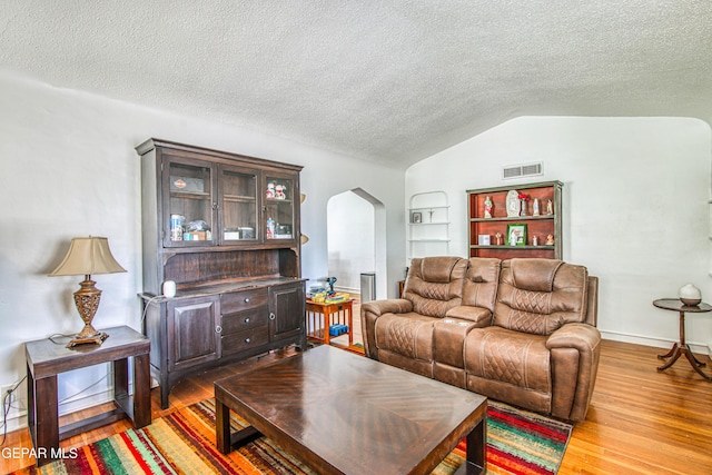 4327 Oxford Ave, El Paso, TX 79903 - living room with arched walkways, wood finished floors, a textured ceiling, lofted ceiling, and built in shelves