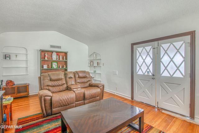 4327 Oxford Ave, El Paso, TX 79903 - living area with built in shelves, a textured ceiling, vaulted ceiling, and light wood finished floors