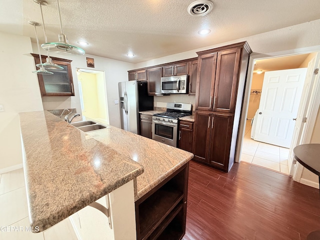 8429 Lasso Cir, El Paso, TX 79907 - kitchen with stainless steel appliances, dark wood-style flooring, a peninsula, dark brown cabinets, and a textured ceiling