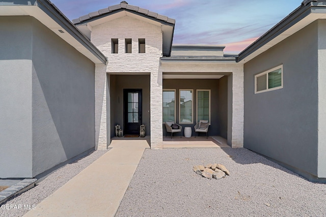 6328 Camino Nogal Dr, El Paso, TX 79932 - exterior entry at dusk with a porch, stone siding, and stucco siding