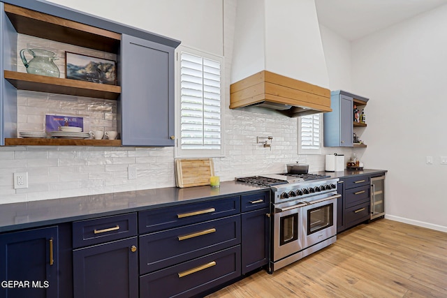 6328 Camino Nogal Dr, El Paso, TX 79932 - kitchen with open shelves, range with two ovens, custom exhaust hood, dark countertops, and light wood-type flooring