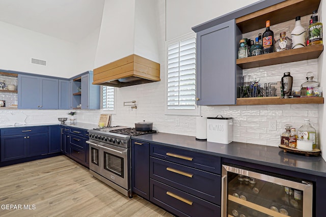 6328 Camino Nogal Dr, El Paso, TX 79932 - kitchen with open shelves, beverage cooler, range with two ovens, blue cabinets, and custom exhaust hood