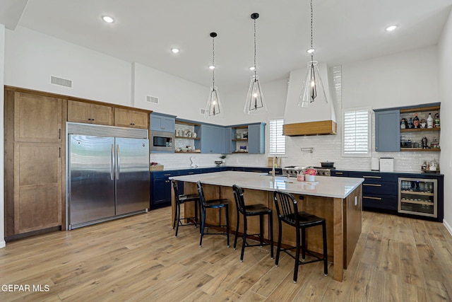 6328 Camino Nogal Dr, El Paso, TX 79932 - kitchen featuring open shelves, built in appliances, beverage cooler, backsplash, and blue cabinetry