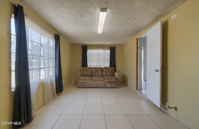 301 Cooley Ave, El Paso, TX 79907 - unfurnished living room featuring a textured ceiling, healthy amount of natural light, and light tile patterned floors