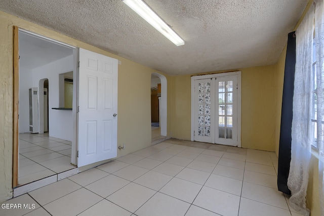 301 Cooley Ave, El Paso, TX 79907 - spare room with arched walkways, a textured ceiling, and light tile patterned flooring