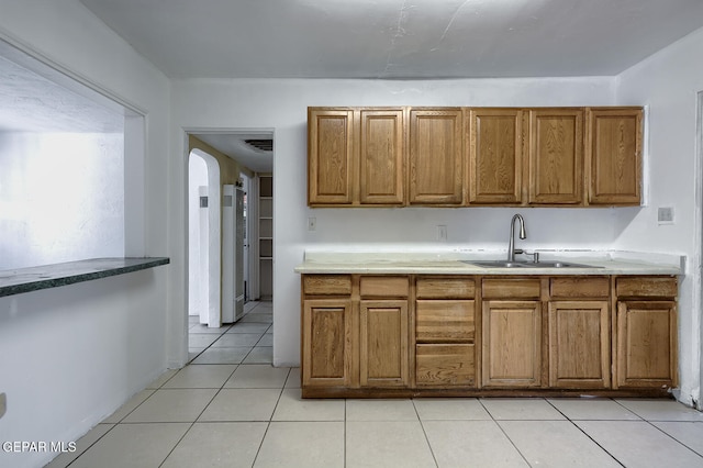 301 Cooley Ave, El Paso, TX 79907 - kitchen with brown cabinets, arched walkways, and light tile patterned floors