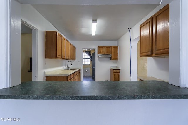 301 Cooley Ave, El Paso, TX 79907 - kitchen with under cabinet range hood, a peninsula, and brown cabinetry