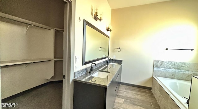 12301 Desert Pine Ave, El Paso, TX 79938 - bathroom with double vanity, a bath, a walk in closet, and wood finished floors