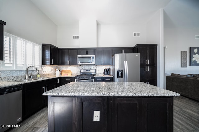 223 Ellesmere Way, El Paso, TX 79928 - kitchen with appliances with stainless steel finishes, a kitchen island, decorative backsplash, light stone countertops, and a high ceiling