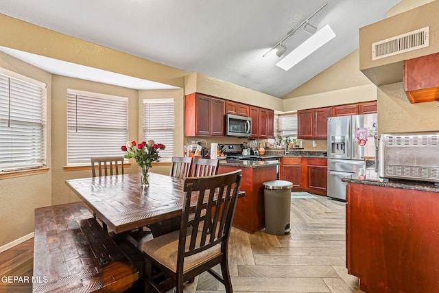 4728 Loma Grande Dr, El Paso, TX 79934 - dining space featuring track lighting, lofted ceiling, a skylight, and a textured wall