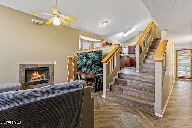 4728 Loma Grande Dr, El Paso, TX 79934 - stairs with a ceiling fan, a tiled fireplace, a textured ceiling, and lofted ceiling
